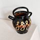 Old vase in glossy black ceramic, vintage exterior decoration.