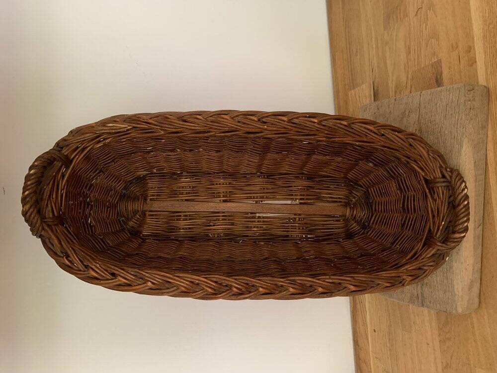 Vintage brown wicker baguette basket, elongated shape, with integrated handles.