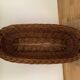Vintage brown wicker baguette basket, elongated shape, with integrated handles.