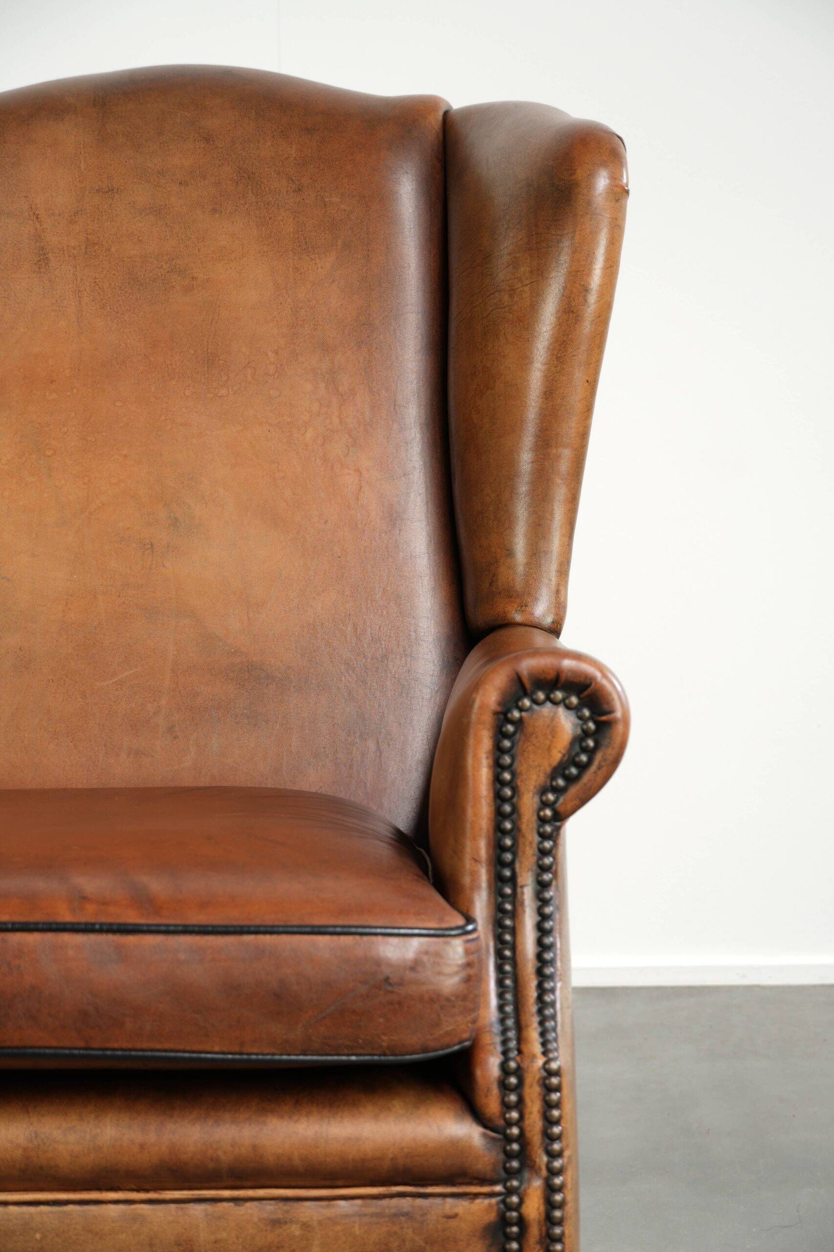 Sheepskin wingback armchair with patina finished with decorative nails