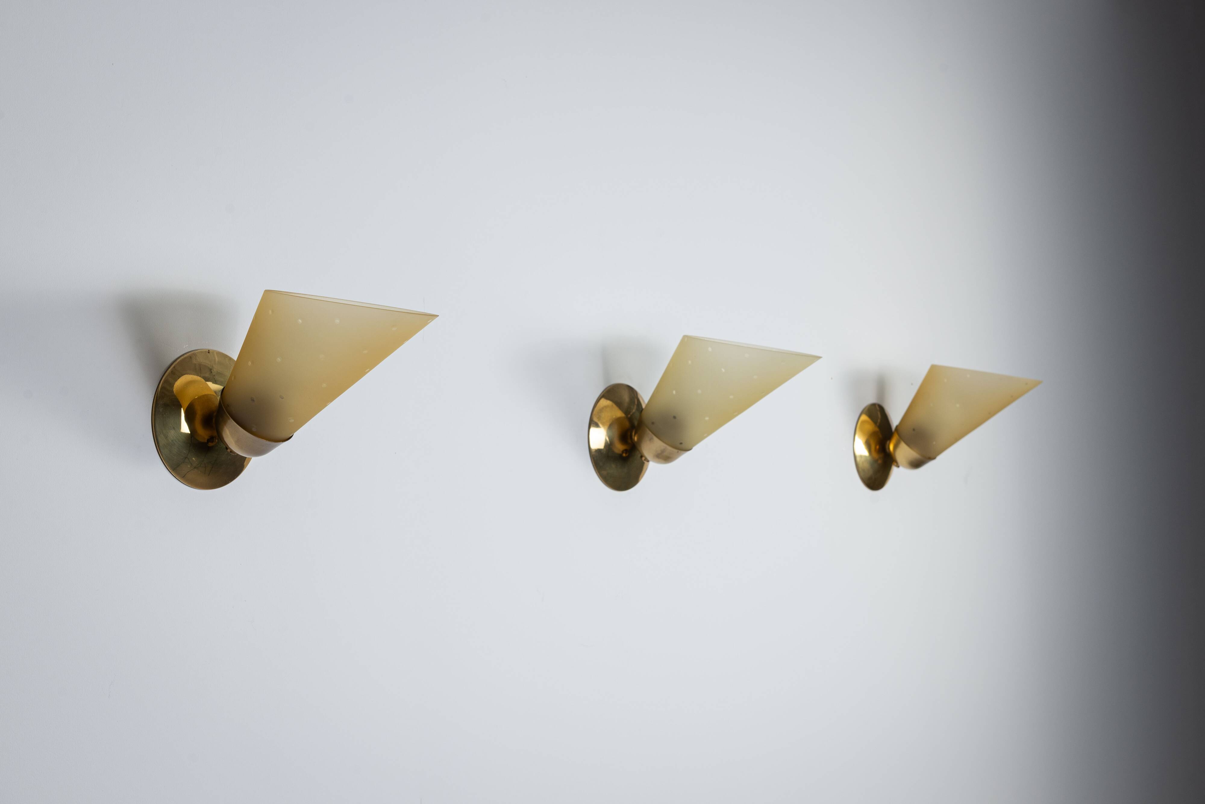 Set of three brass sconces with decorated yellow glass shades