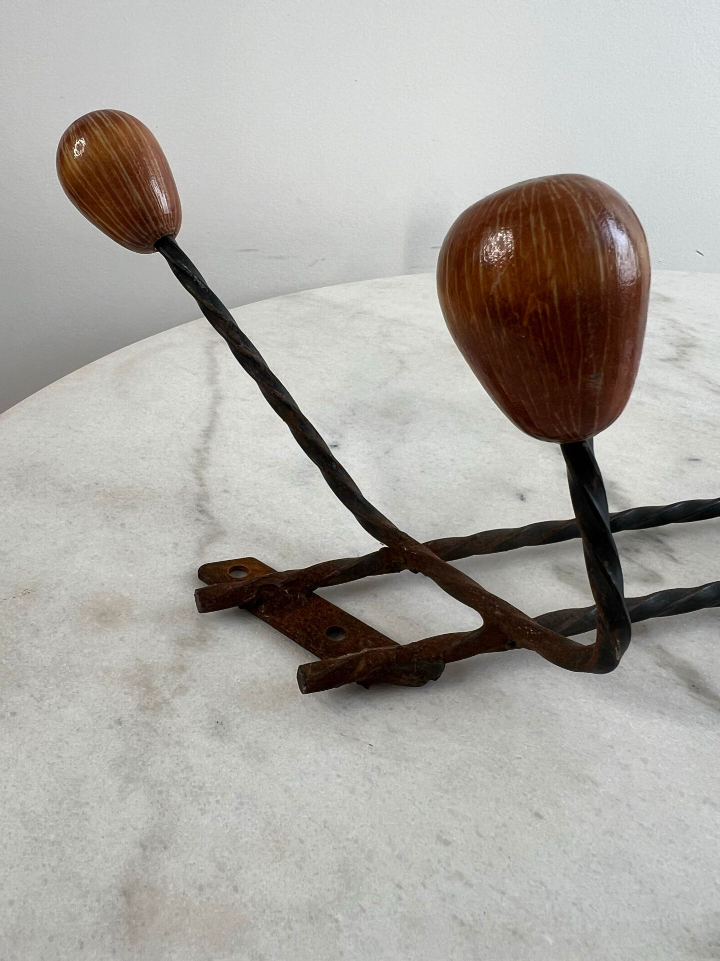Wall-mounted coat rack in wrought iron with turned wooden knobs.