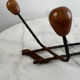 Wall-mounted coat rack in wrought iron with turned wooden knobs.