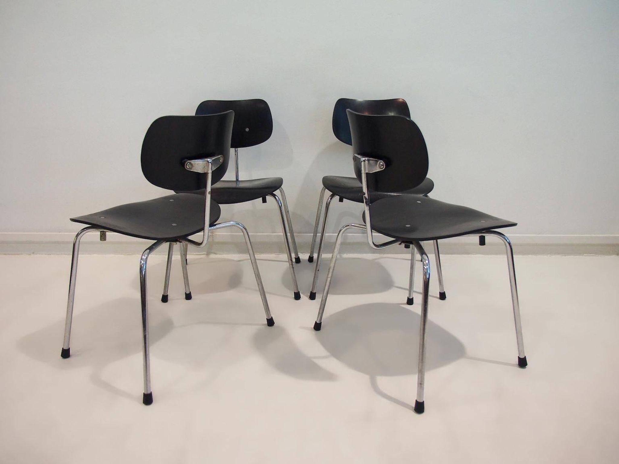 Set of four Egon Eiermann model SE 68 chairs in black lacquered plywood and steel.