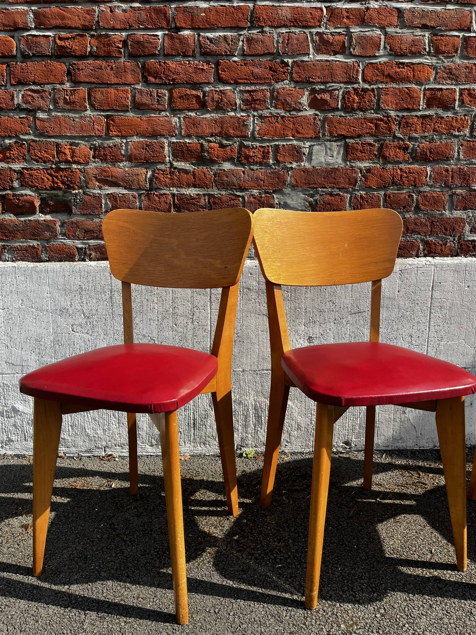 Set of 4 vintage bistro chairs in wood and red faux leather, with splayed legs.