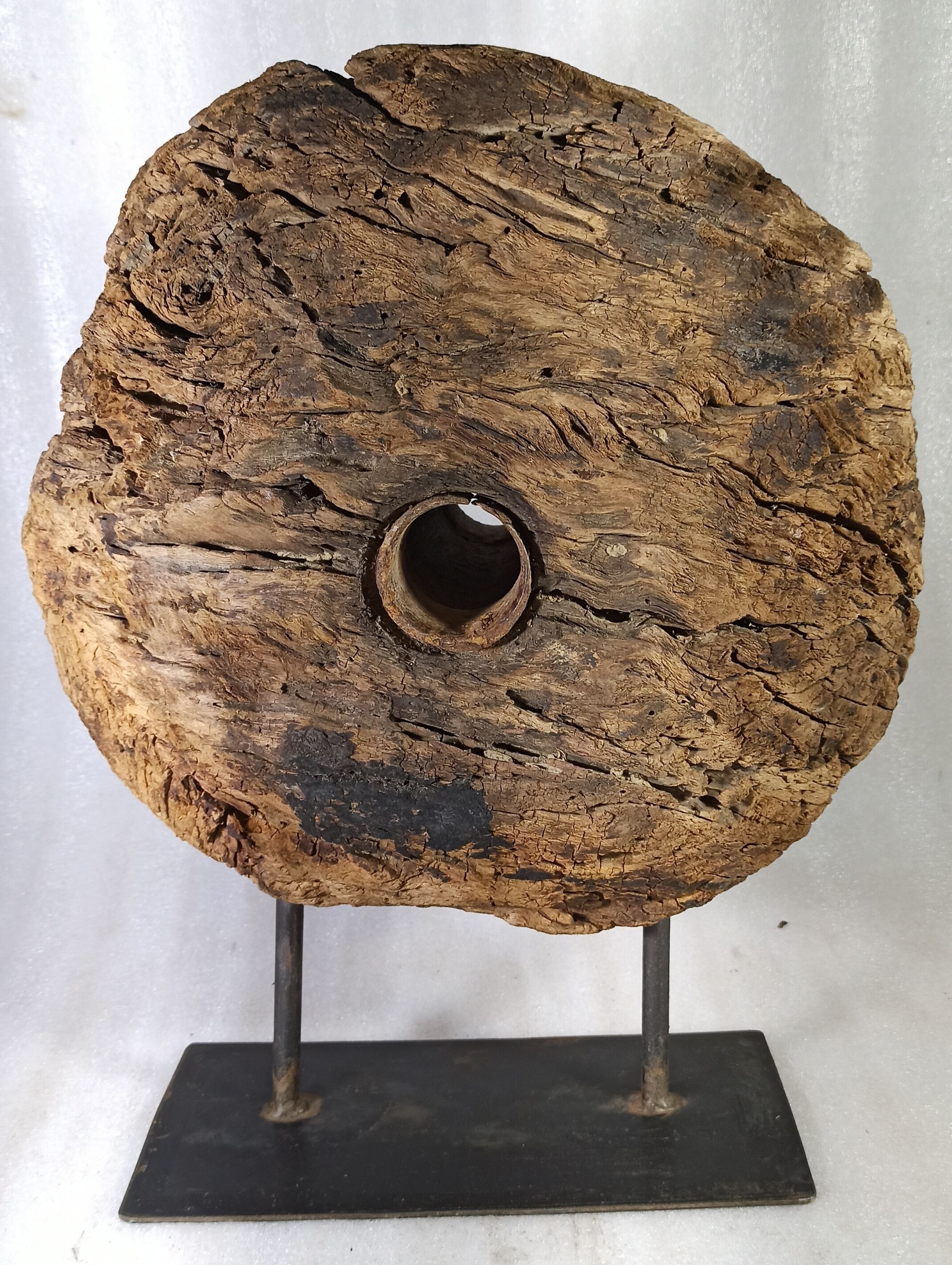 Old wooden pulley wheel on foot