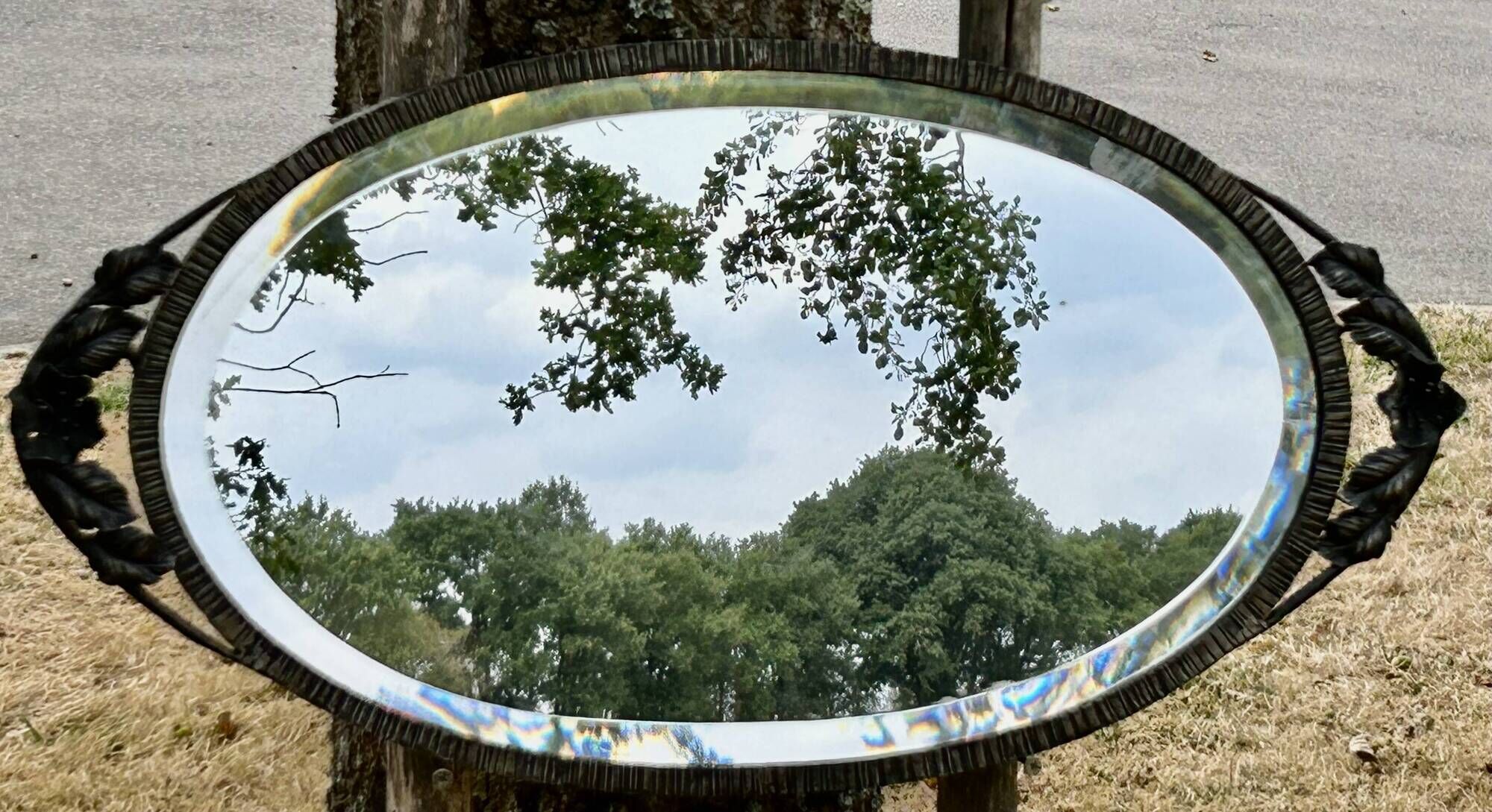 Bevelled oval mirror, richly crafted Art Deco wrought iron.