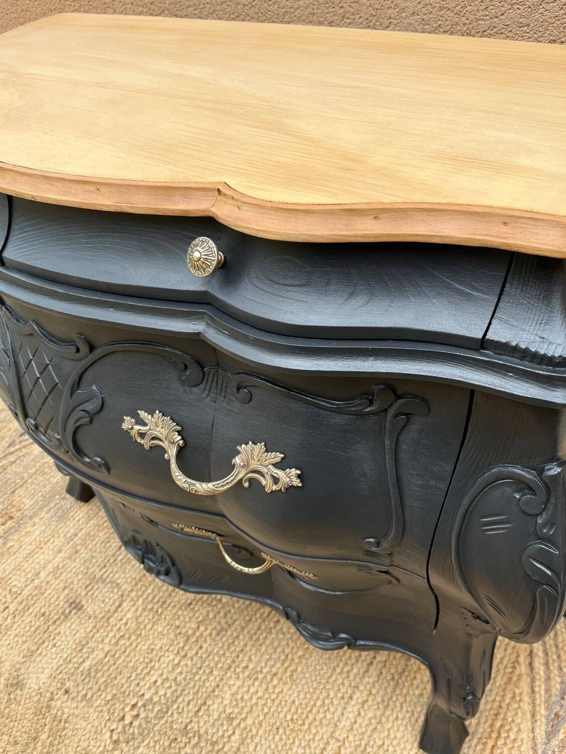 Curved commode painted in black and wood.