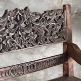 Small antique Indonesian bench in carved teak with plant and floral motifs.