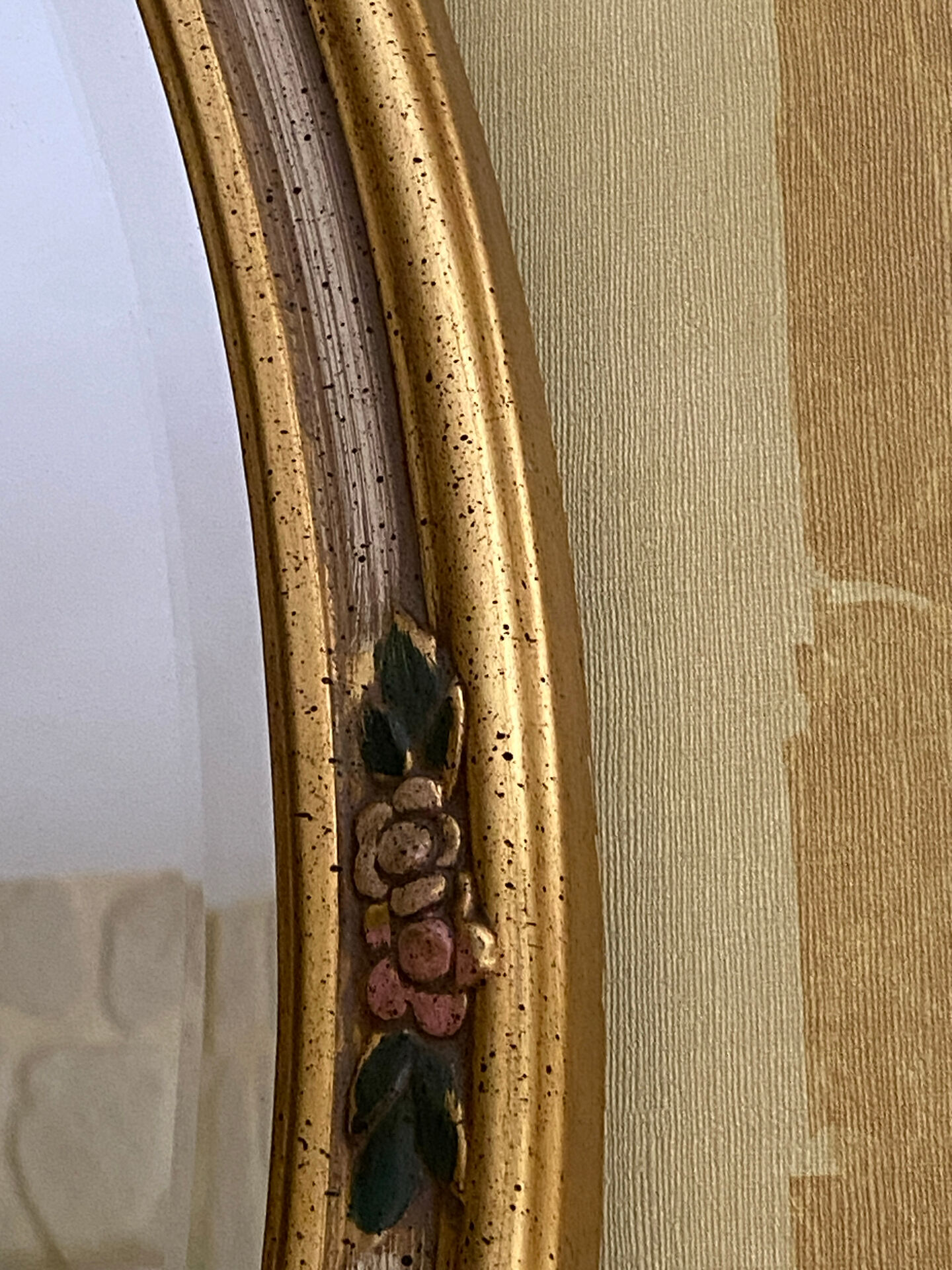 Oval wooden frame with floral decoration in gold.