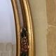Oval wooden frame with floral decoration in gold.