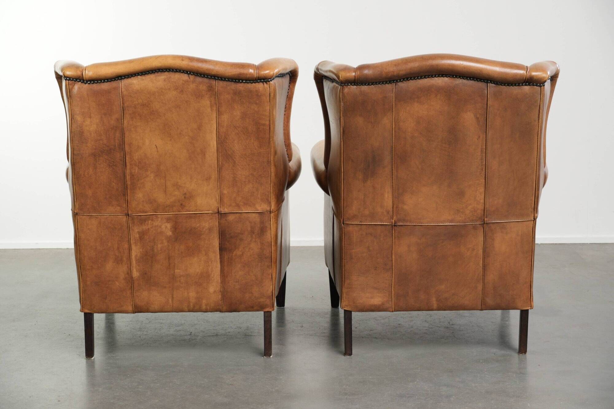 Set of two light cowhide wingback armchairs with a timeless English look