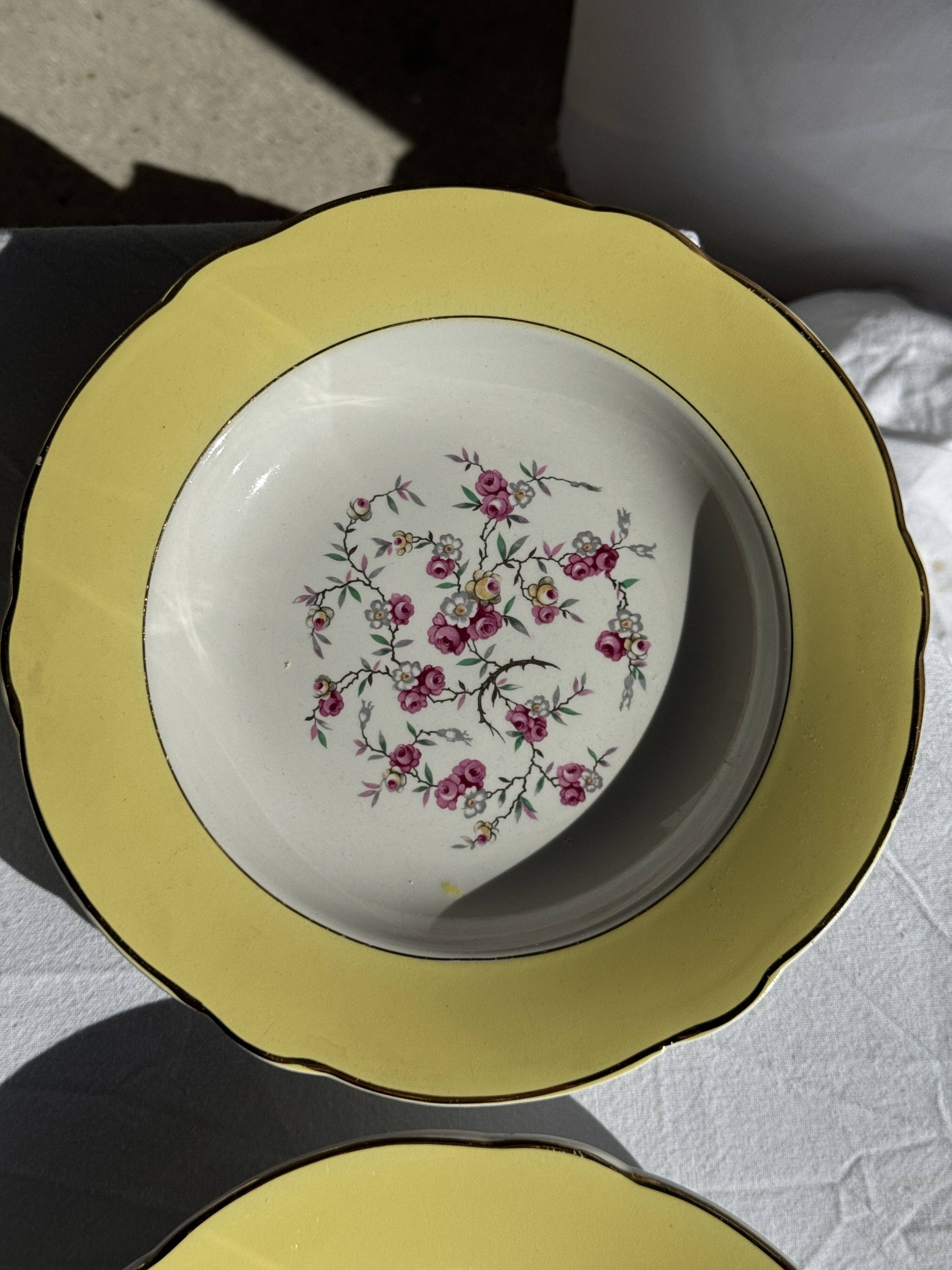 Set of 9 large vintage yellow deep plates with pink flowers and a gold rim.