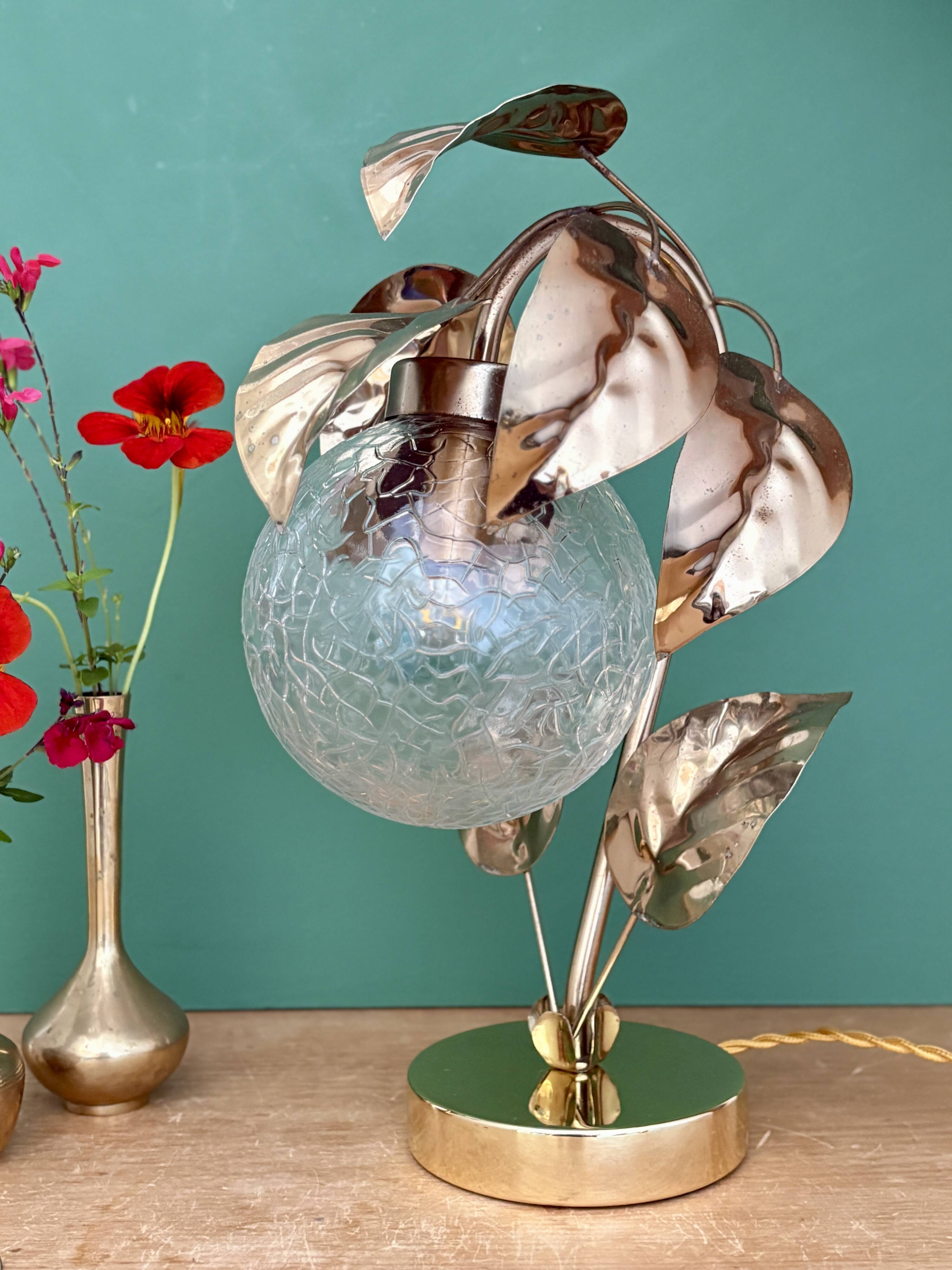 Vintage lamp with brass leaf design and transparent glass globe.