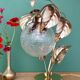 Vintage lamp with brass leaf design and transparent glass globe.