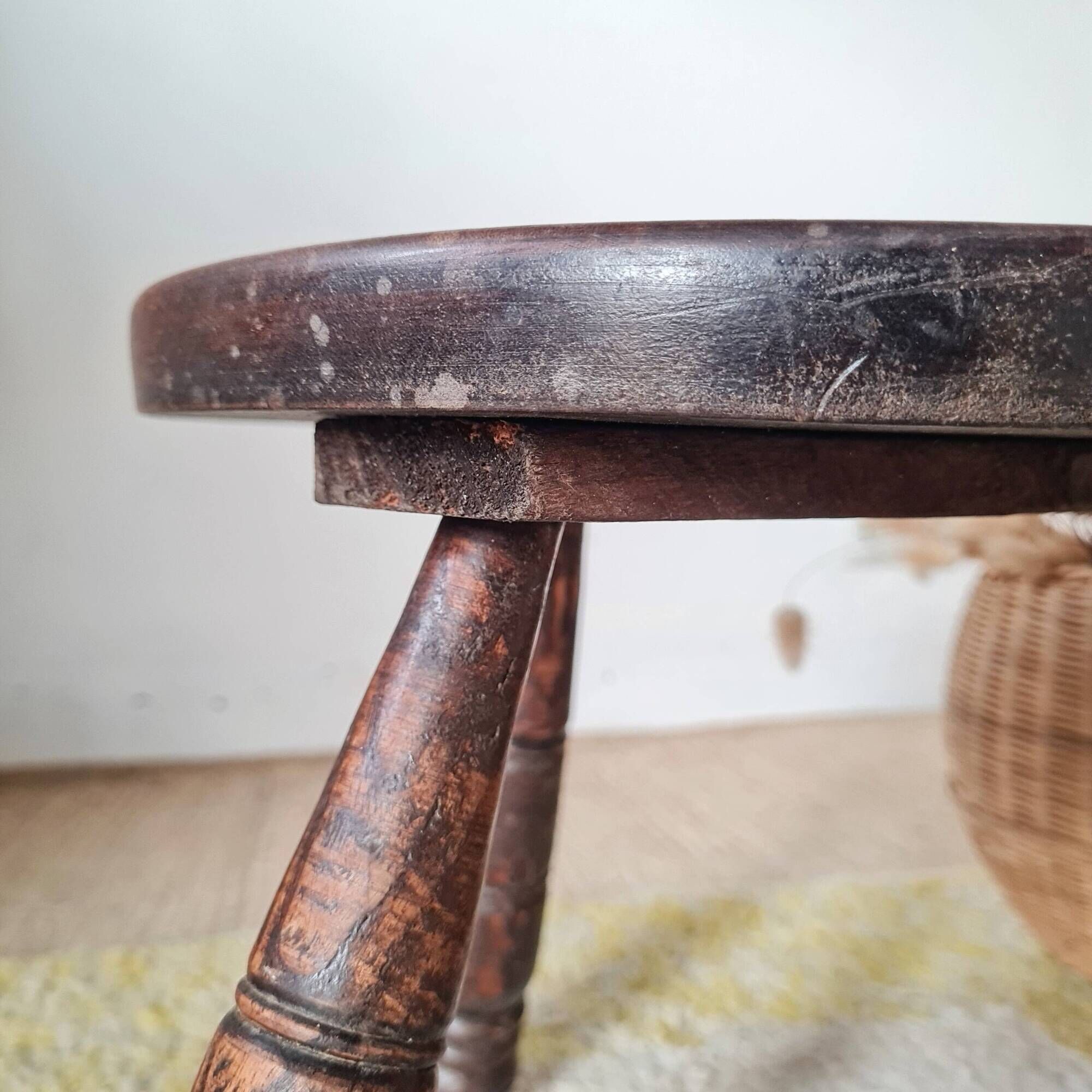 Small brutalist tripod stool made of turned wood.