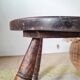 Small brutalist tripod stool made of turned wood.