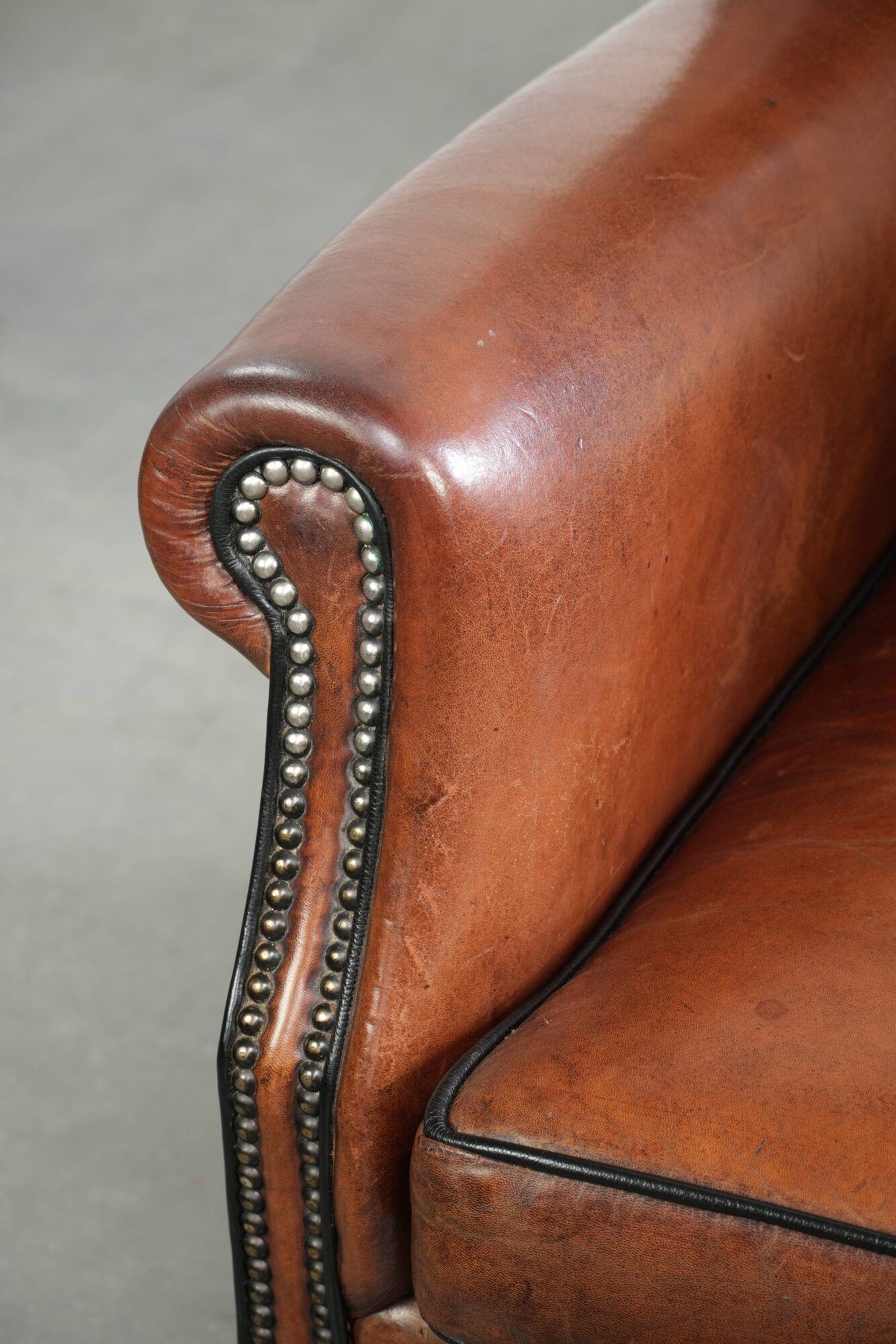 Sheepskin wingback armchair in a warm cognac colour with refined nailhead trim