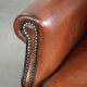 Sheepskin wingback armchair in a warm cognac colour with refined nailhead trim