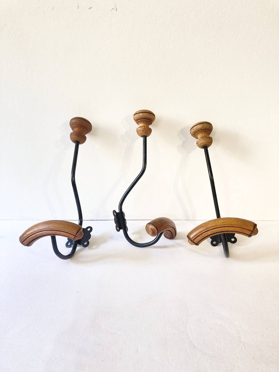 Trio of antique wooden and metal coat hooks