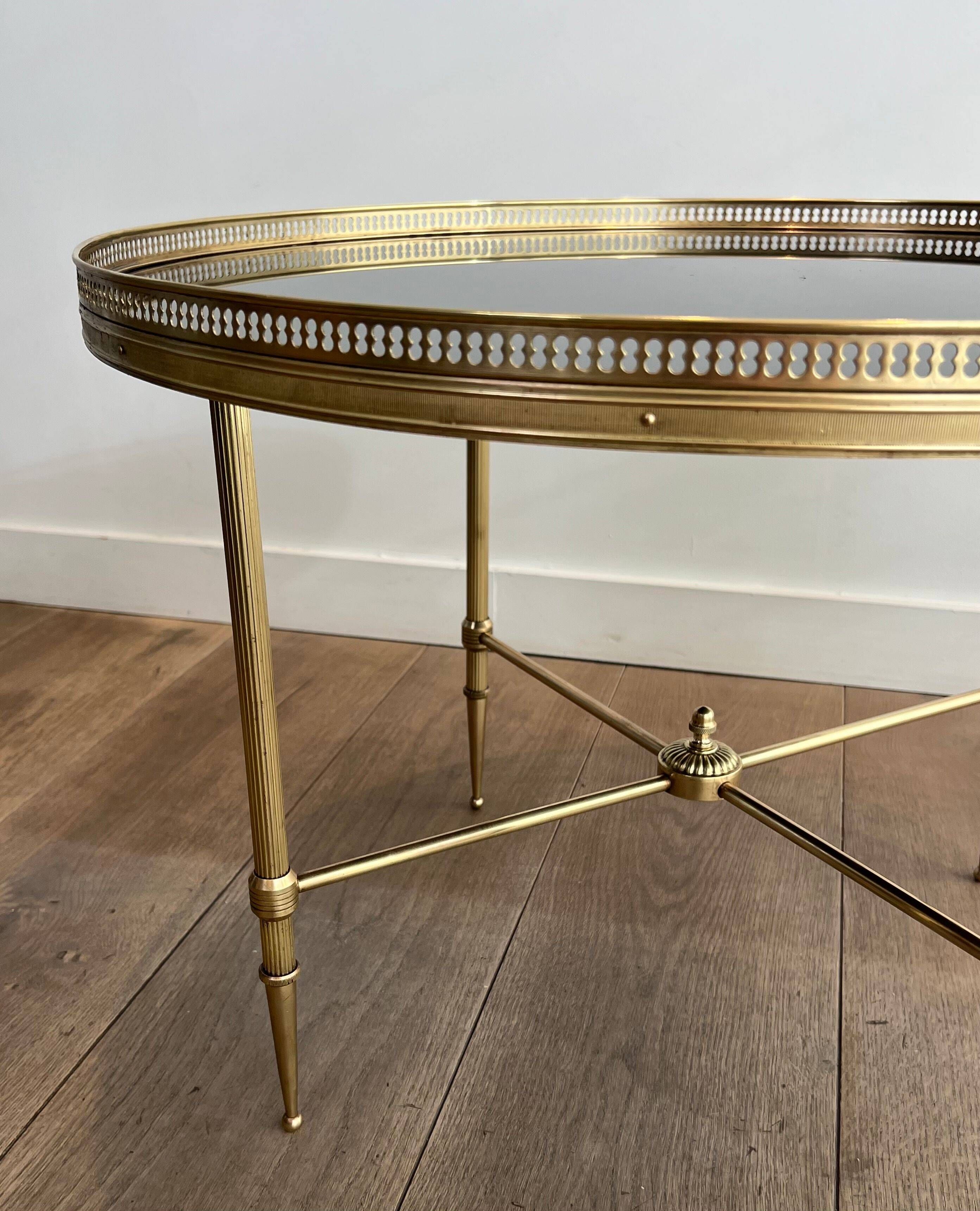Round coffee table in brass with a black lacquered glass top from Maison Jansen.
