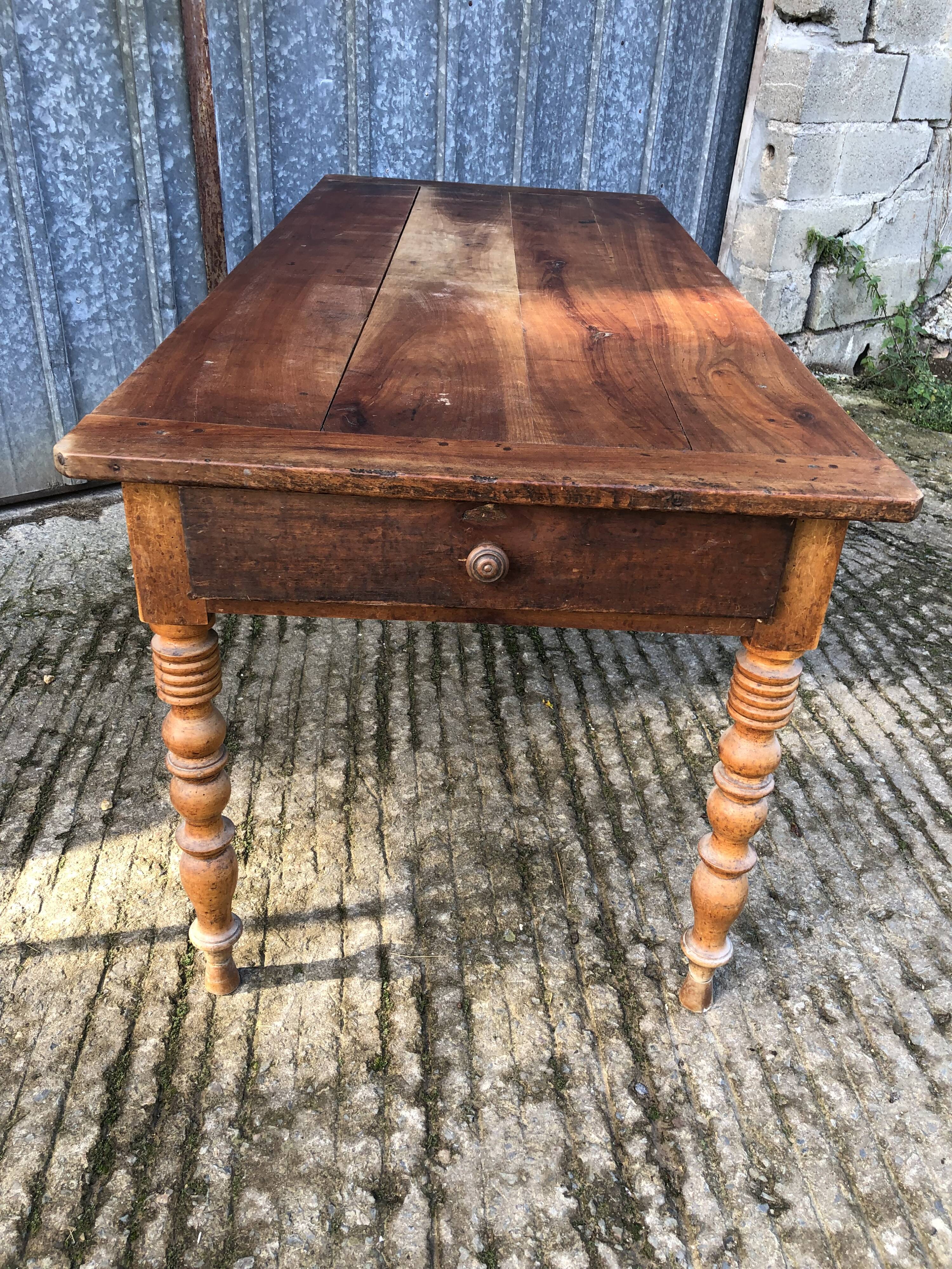 Antique farmhouse table in solid cherry wood with turned legs.