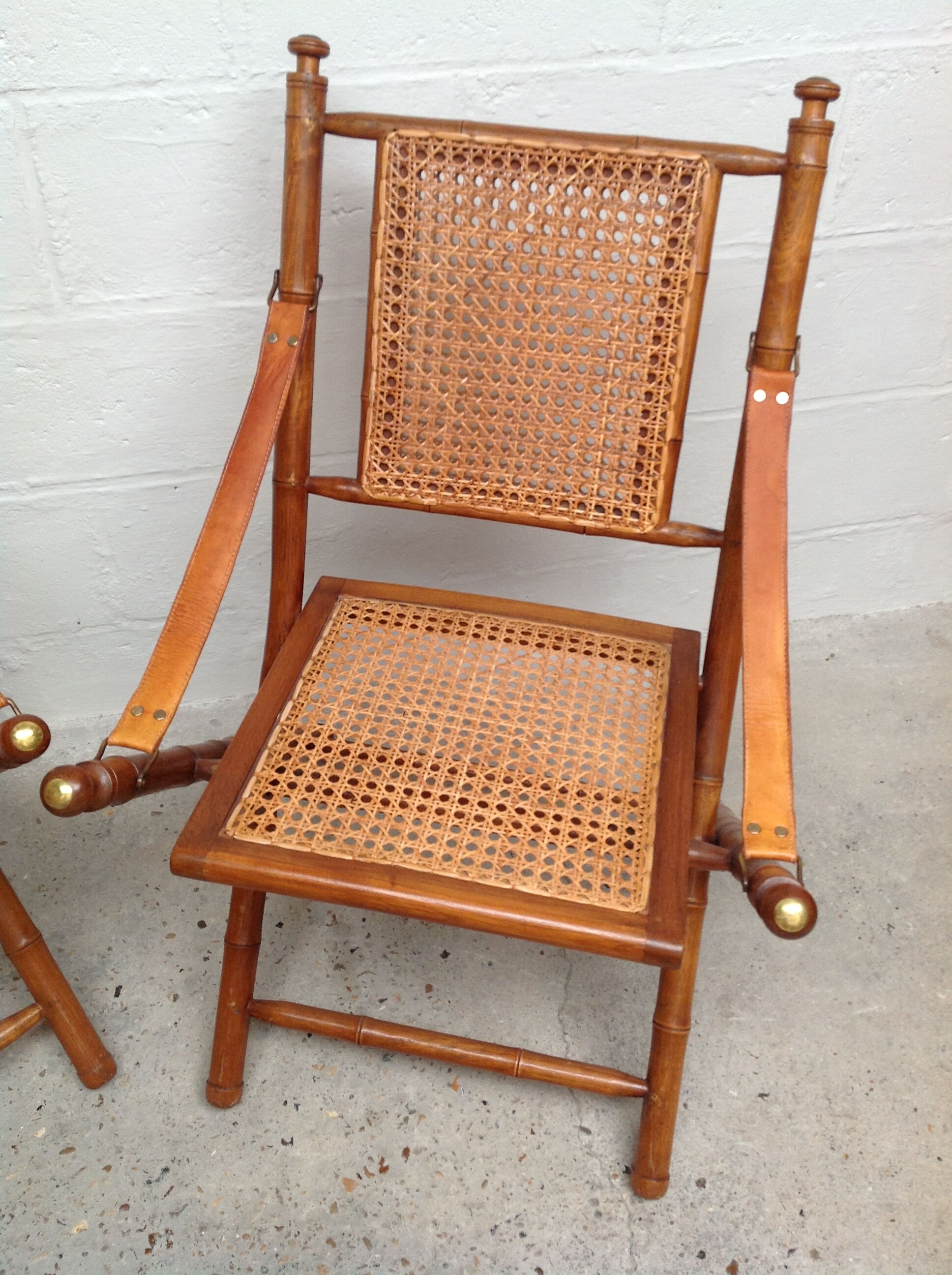 Pair of folding chairs in bamboo and caning, leather and brass