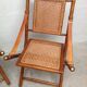 Pair of folding chairs in bamboo and caning, leather and brass