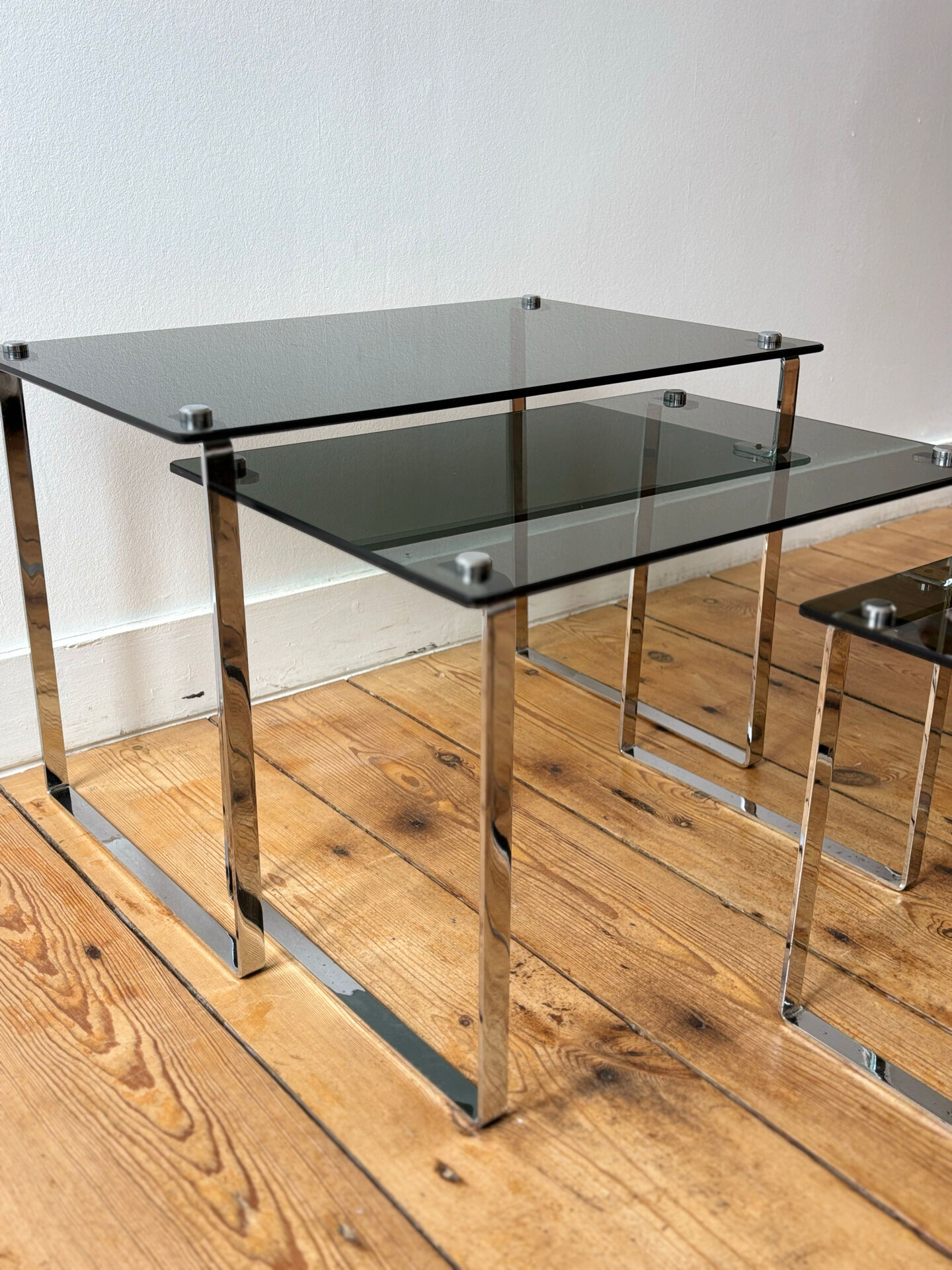 Nest of coffee tables in chrome with smoked glass top.