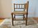 Antique corner chair by the fire with turned wood and straw seat.