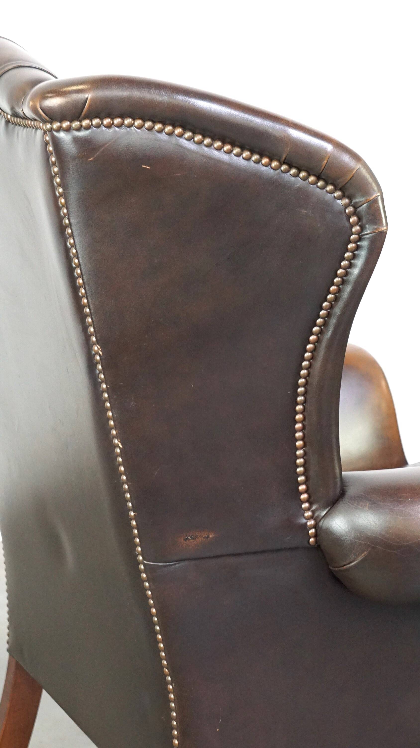 Chesterfield wing chair in dark brown leather with a luxurious appearance