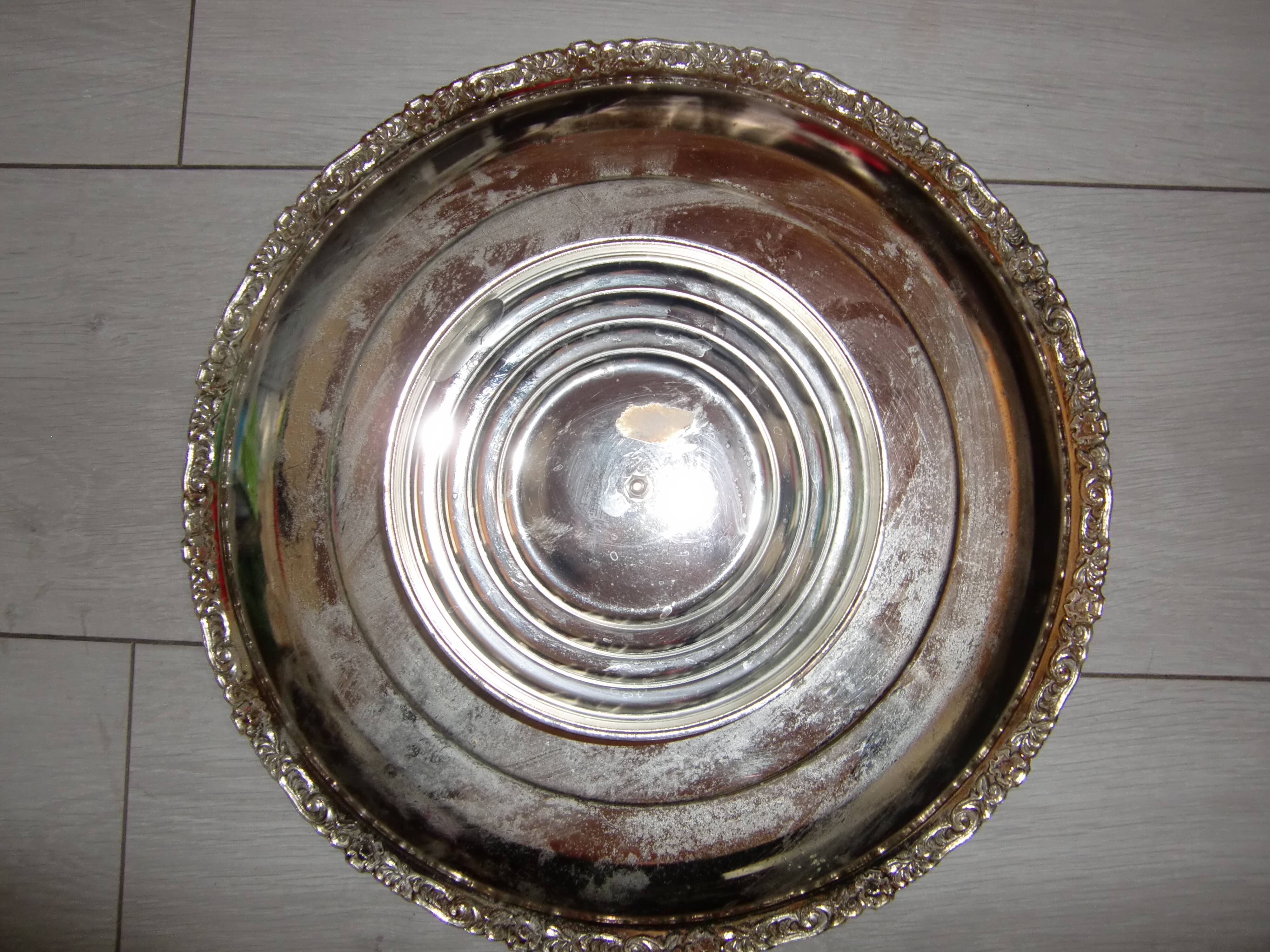 Large silver metal tray raised by a central foot