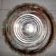 Large silver metal tray raised by a central foot
