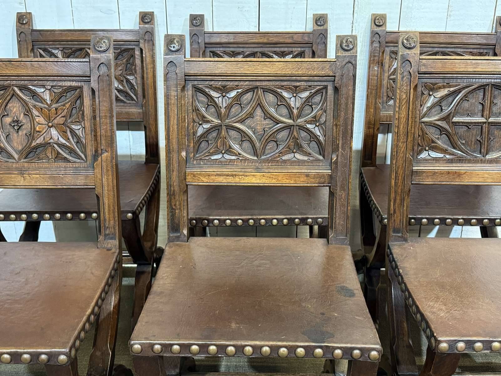 Suite de 6 chaises et 2 fauteuils en chêne et cuir à décor gothique