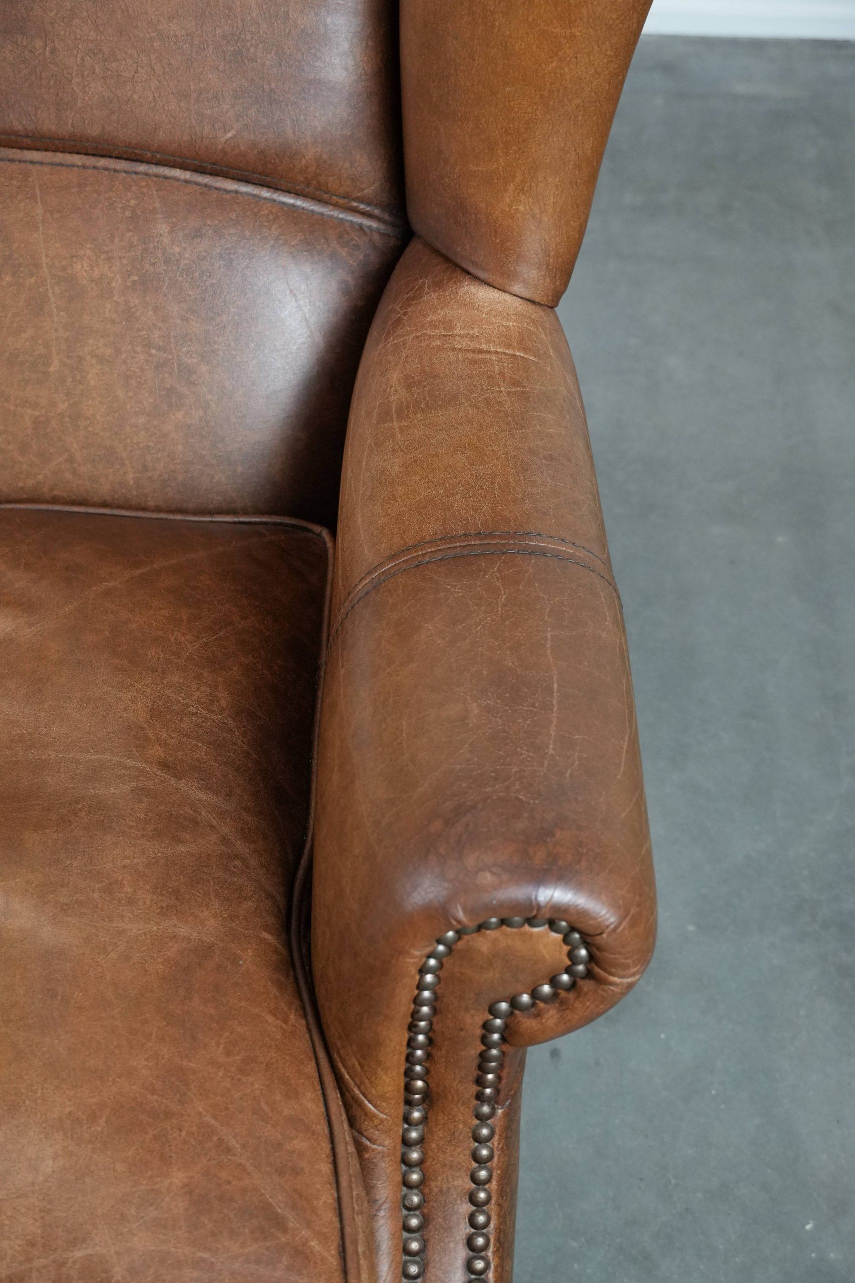 Cognac-coloured wingback armchair in English style made of cowhide leather