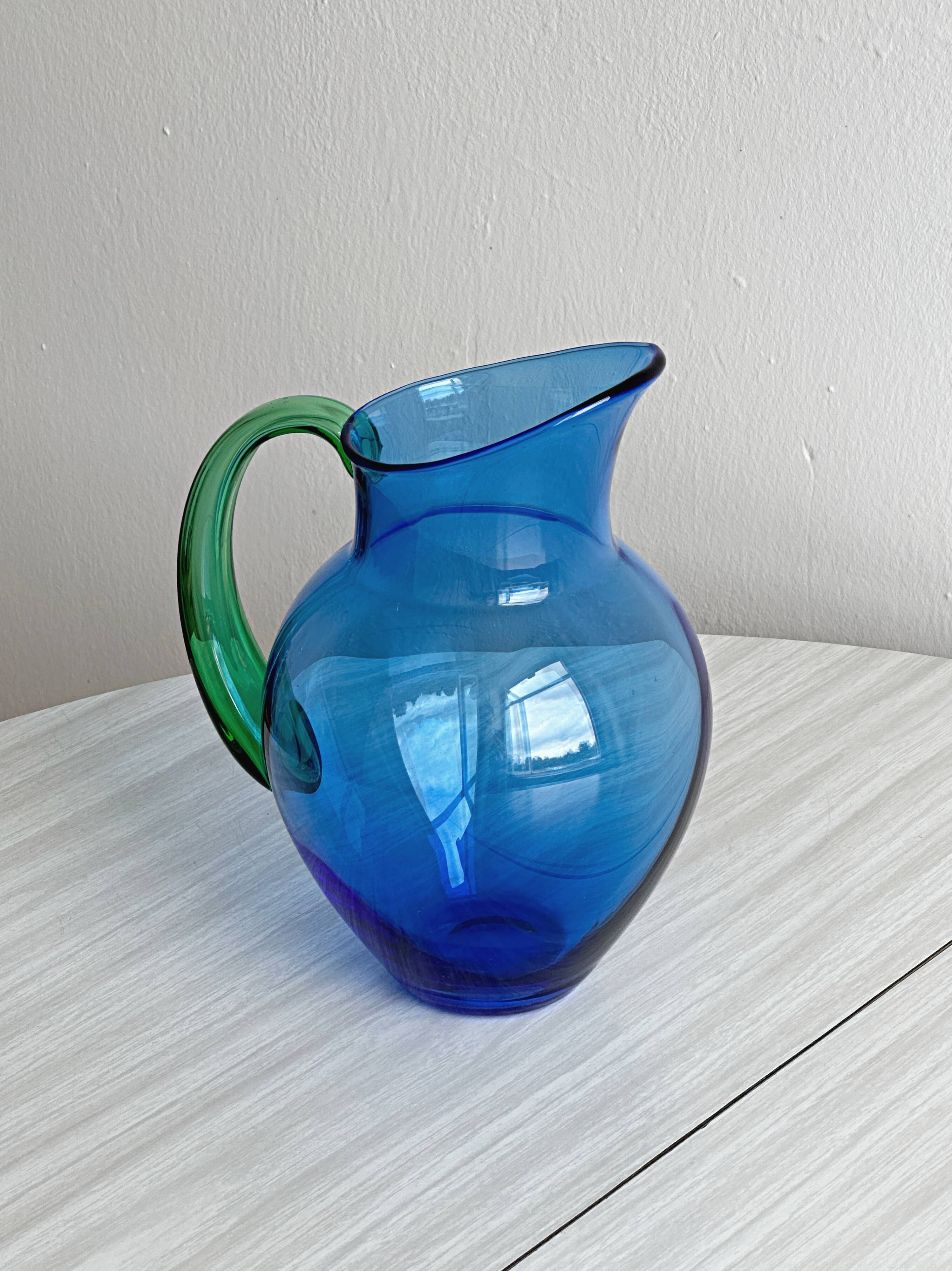 Translucent blue glass jug with a green handle.