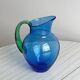 Translucent blue glass jug with a green handle.