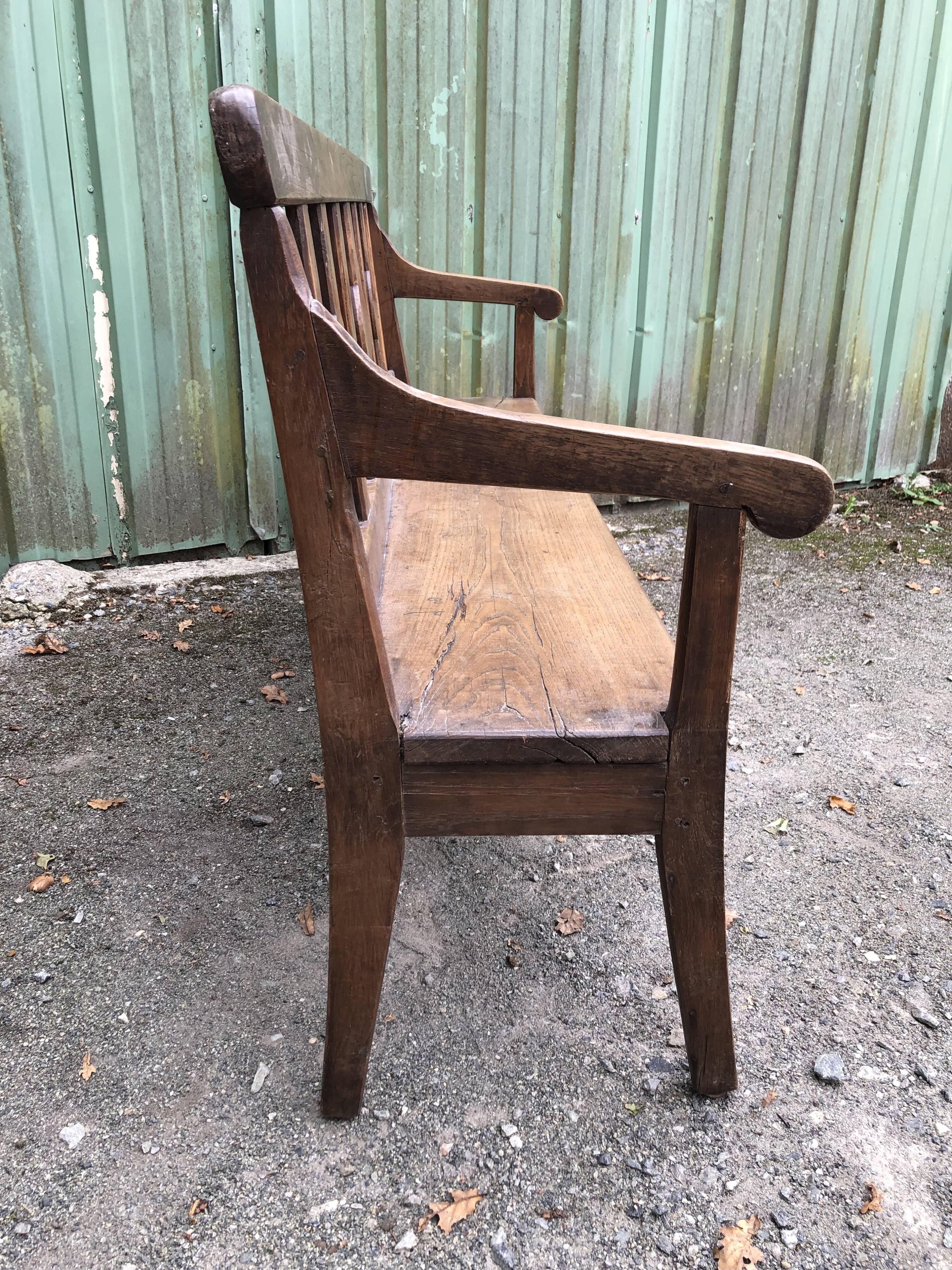 Duo of old solid oak benches with backs and armrests.