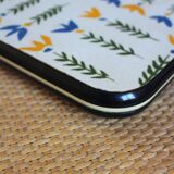 Vintage laminated wooden trivet with yellow, green, and blue flowers