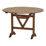 19th-century French round wine table with an adjustable top and floral textile surface.