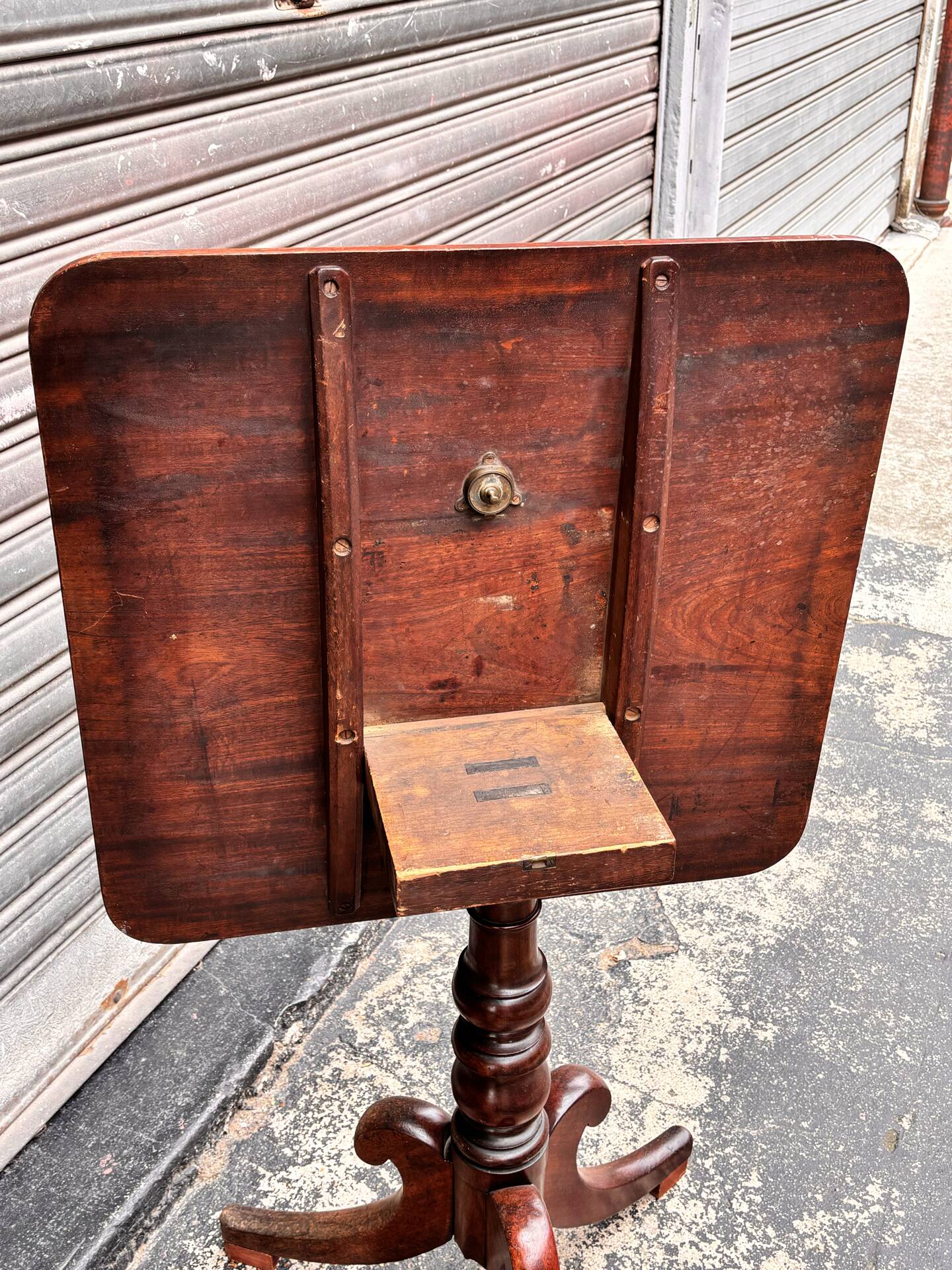 19th-century solid mahogany table with a tilting top and brass mechanism.