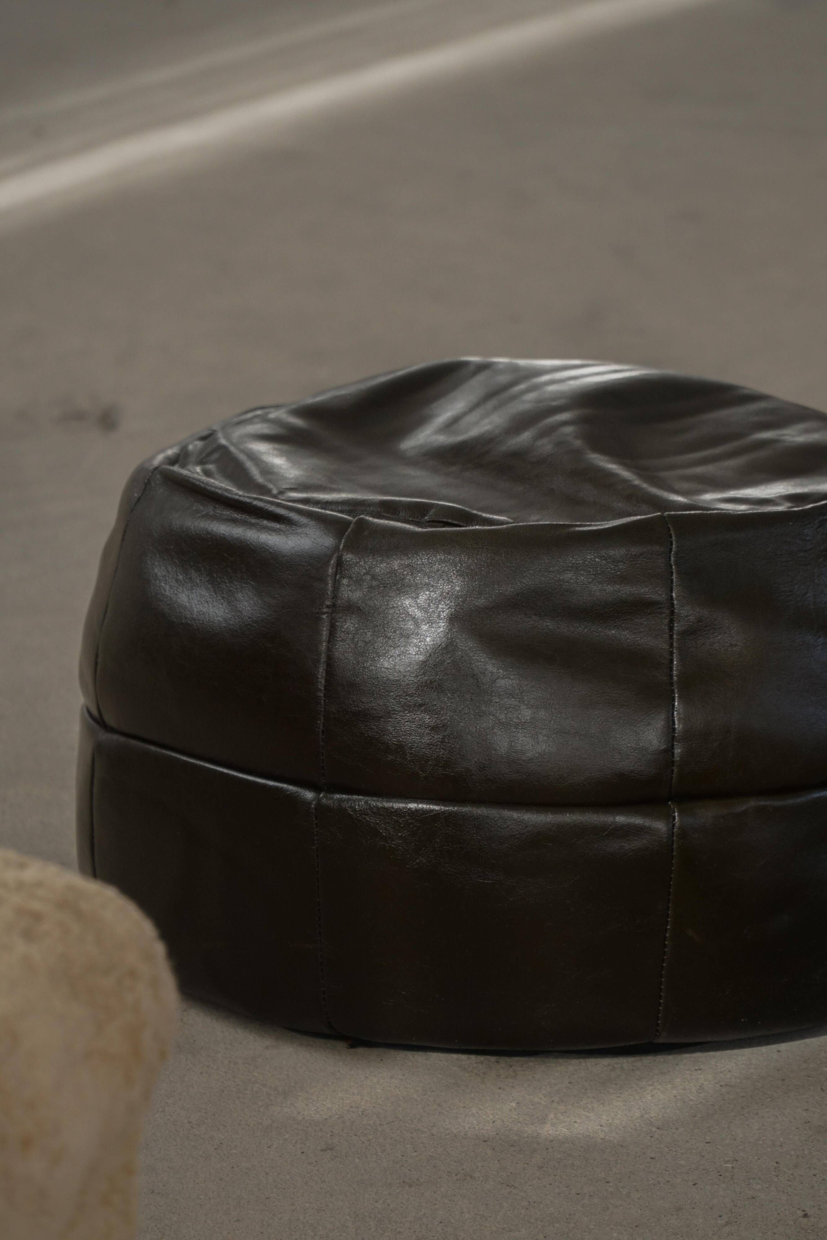 Vintage black leather pouf/ottoman with a rounded shape, French mid 20th Century.