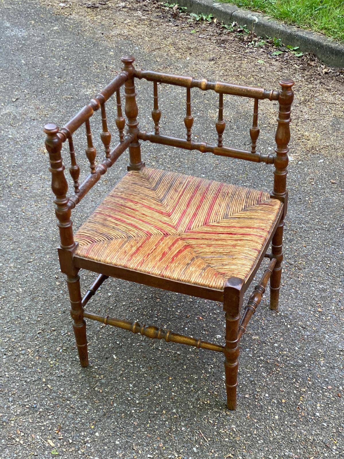 19th-century solid wood corner chair with red and blue rush seating.