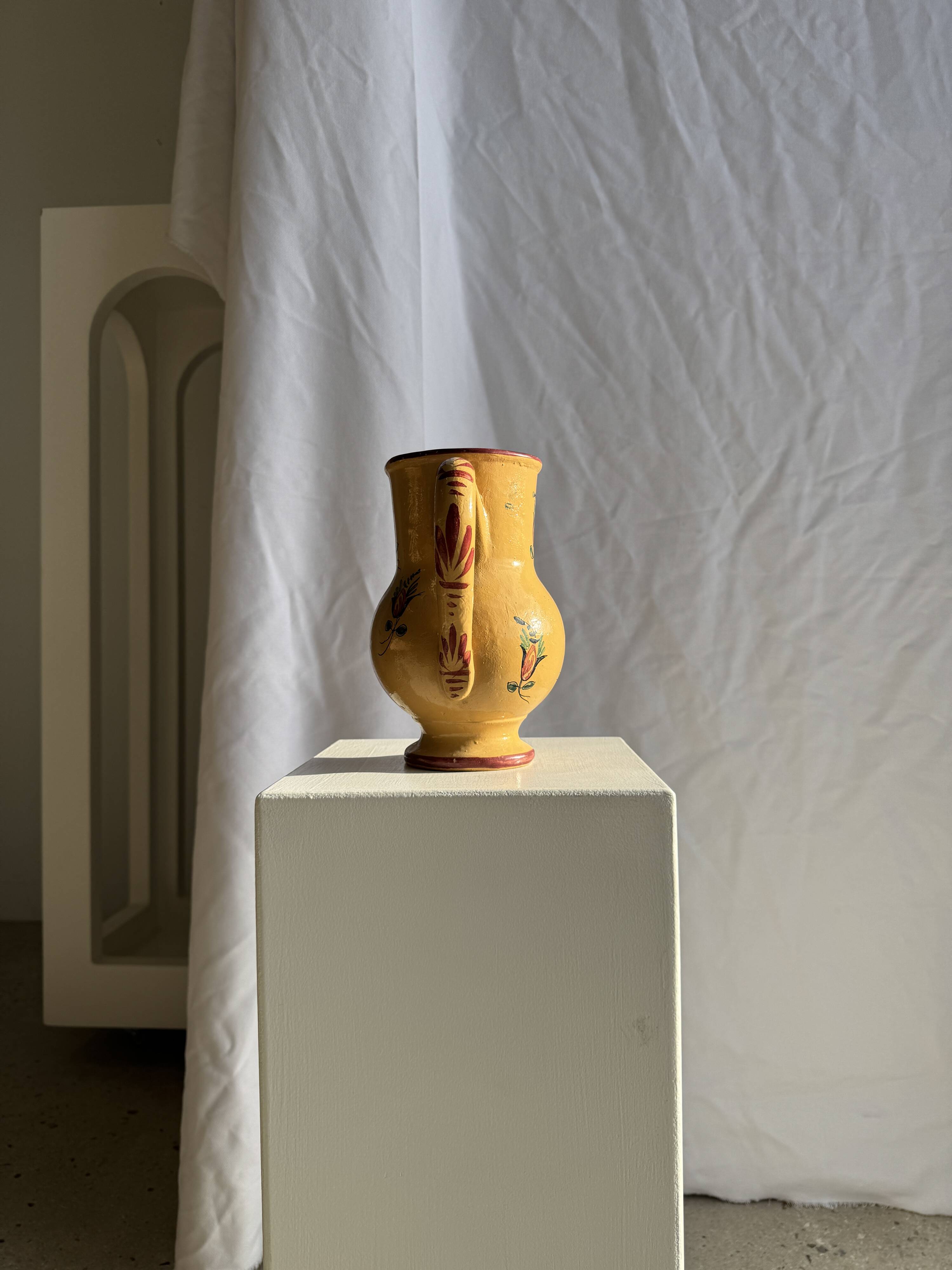 Large antique handmade ochre yellow jug with a pink flower pattern.