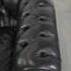 Set of a black cowhide leather Chesterfield armchair and matching ottoman
