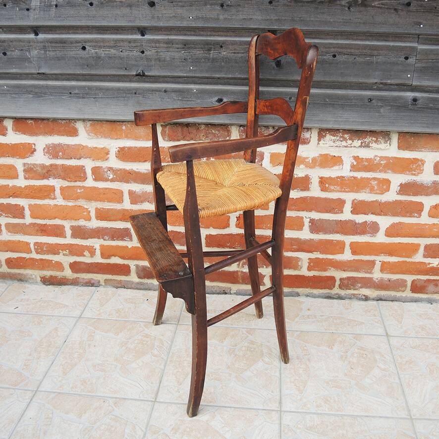 Old wooden high chair for children with straw.