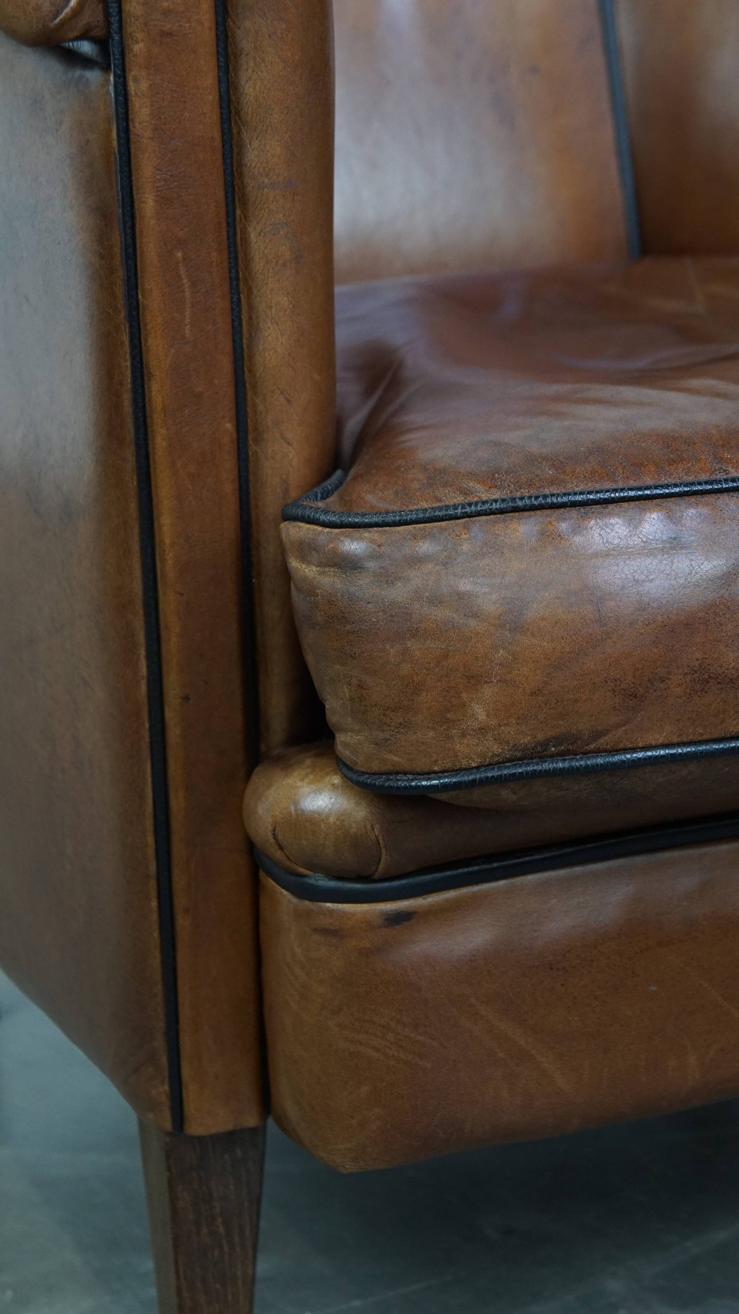 Unique vintage cognac-coloured leather club armchair with black piping
