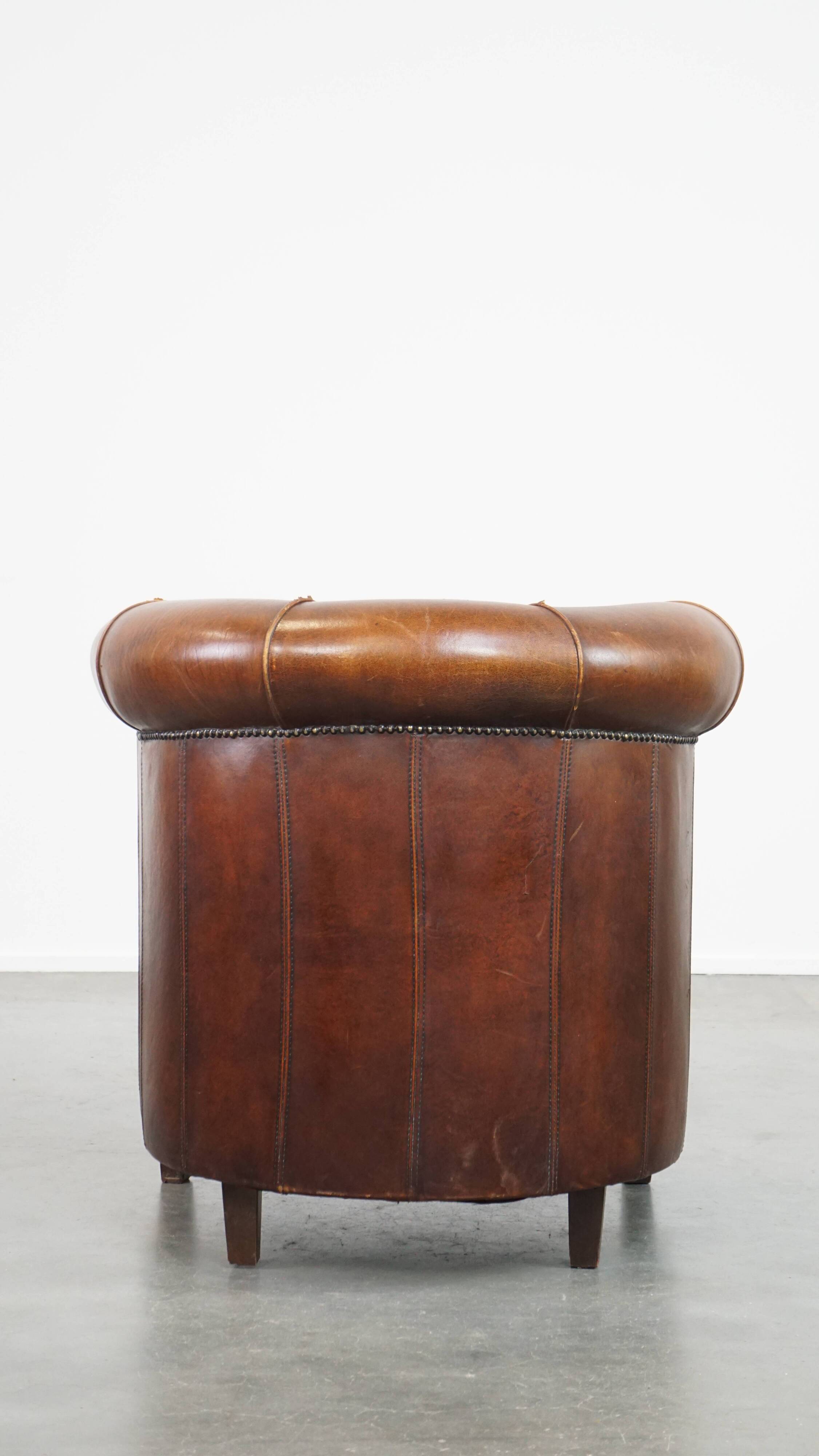 Sheep leather club chair in a cognac color and finished with piping
