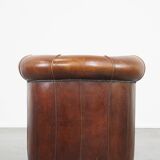 Sheep leather club chair in a cognac color and finished with piping