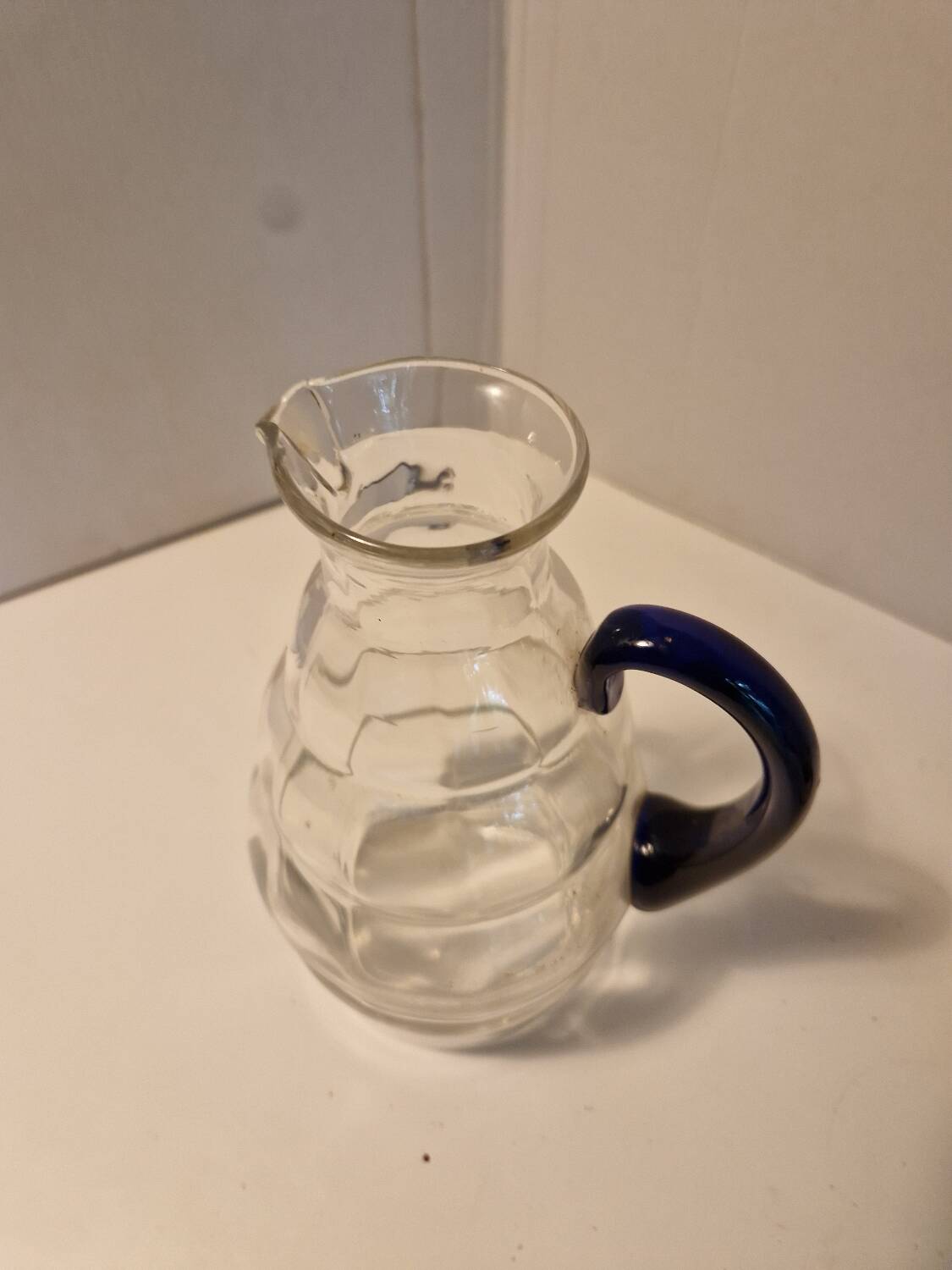 Glass carafe with wavy body and blue handle
